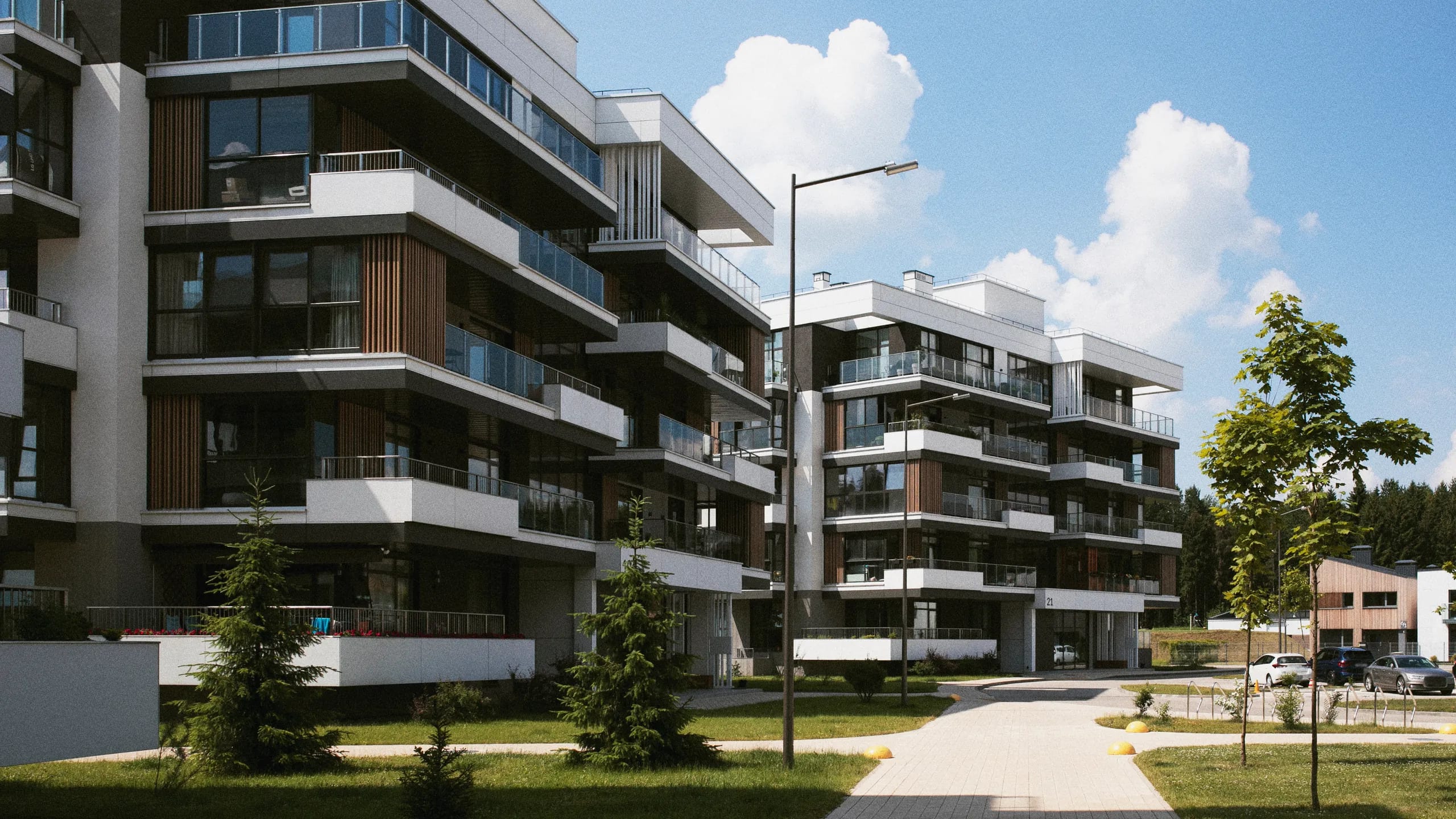 A recently completed apartment development with balconies and landscaped grounds under a clear sky.